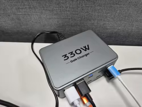 Charging station on a white desk with several cables plugged into its front ports
